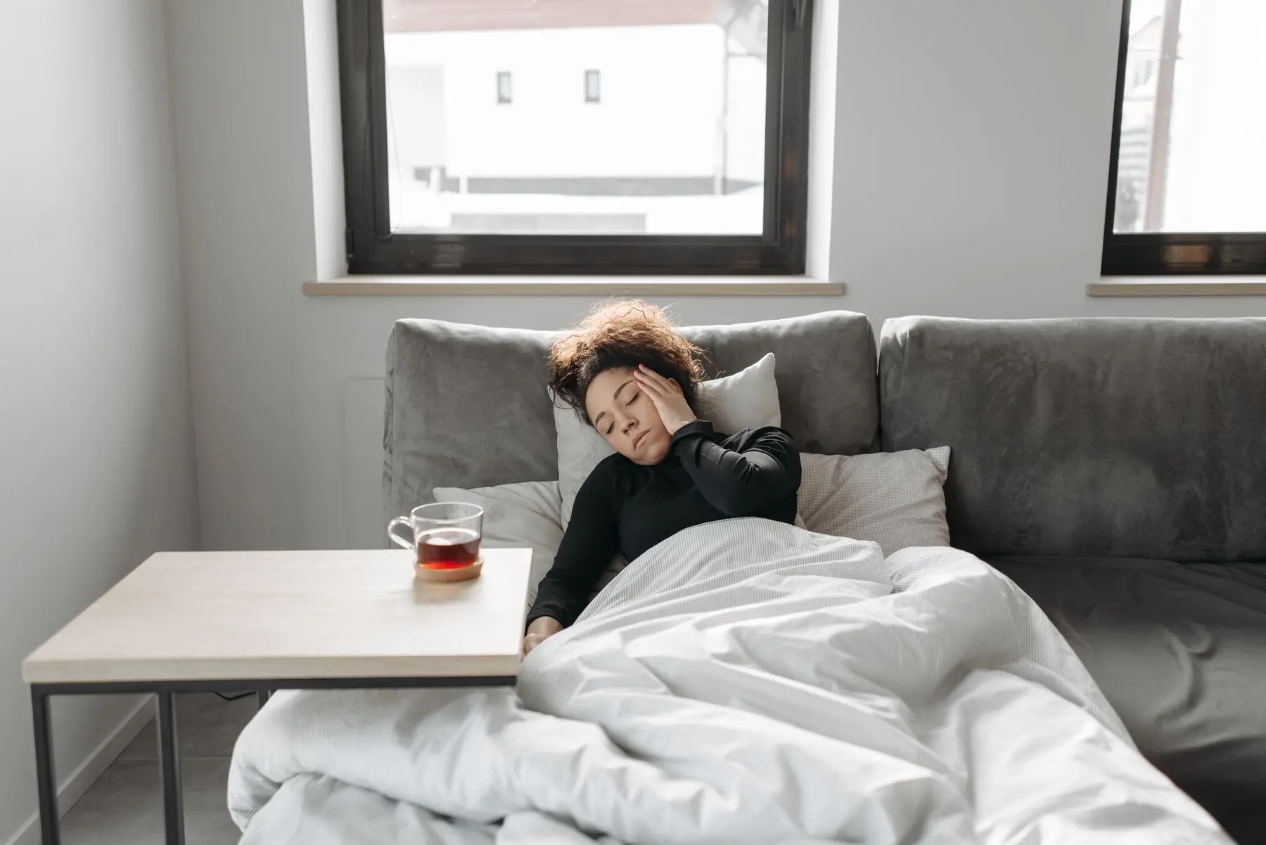 Frau ruht auf dem Sofa, daneben eine Tasse Tee