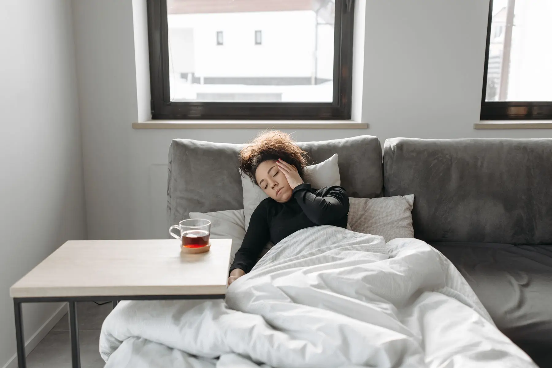 Frau ruht auf dem Sofa, daneben eine Tasse Tee