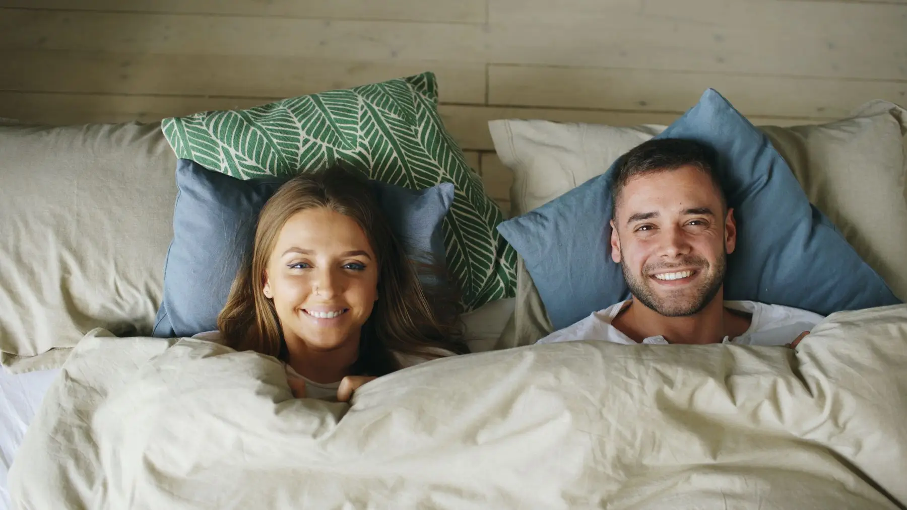 Lächelndes Paar liegt entspannt im Bett